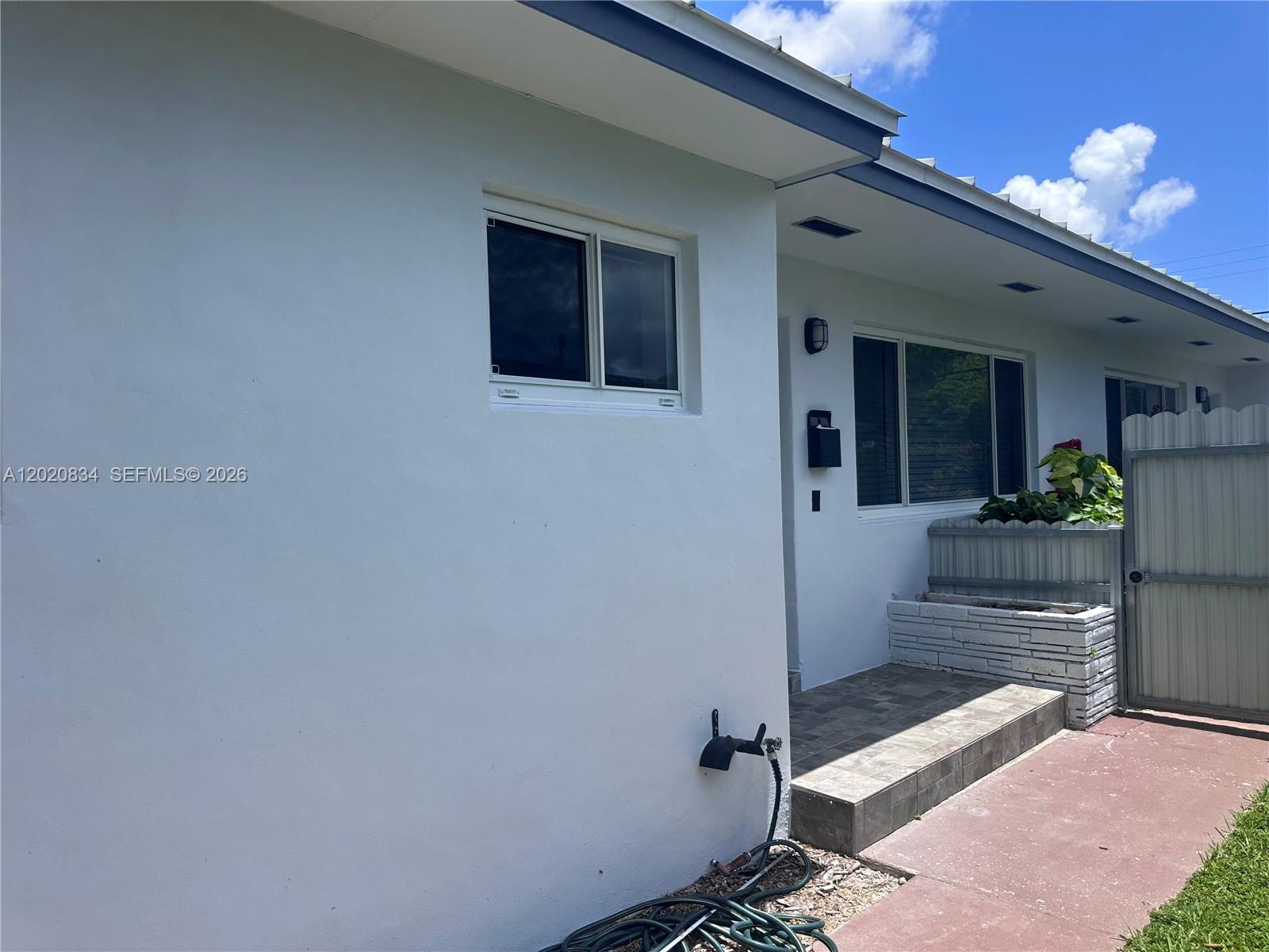 A white exterior wall features a small window, a tiled entryway, and a garden bed — 2806 SW 35th Ave # 1, Miami FL 33133, MIAMI, FL