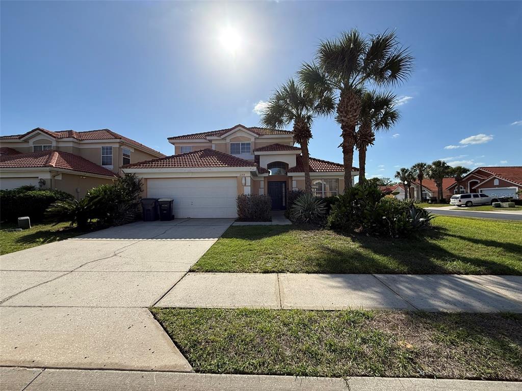 A two-story house with a white garage, tile roof, and palm trees in the front yard — 1153 SOLANA CIRCLE UNIT 1153, DAVENPORT, FL
