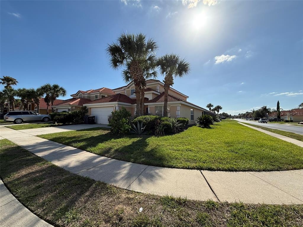 A two-story house with a tiled roof, palm trees, and a lawn under a sunny sky — 1153 SOLANA CIRCLE UNIT 1153, DAVENPORT, FL