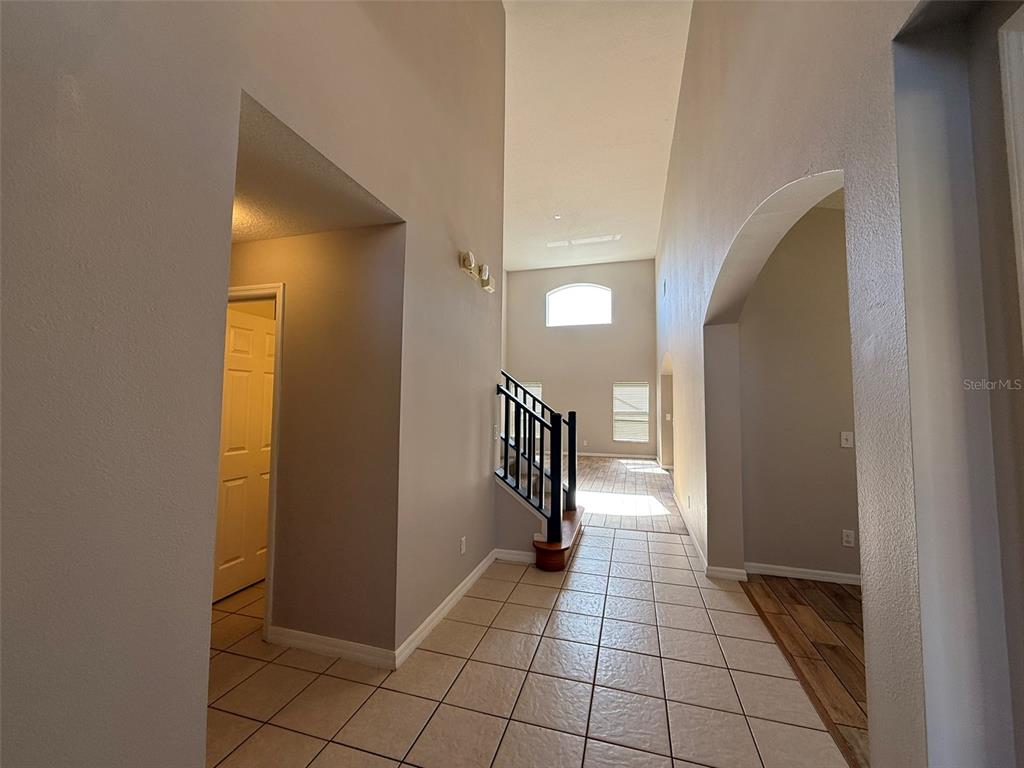 A tiled entryway leads to a staircase with a black railing and a high ceiling — 1153 SOLANA CIRCLE UNIT 1153, DAVENPORT, FL