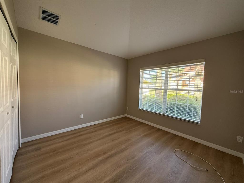 An empty bedroom with light-colored walls, wood-look flooring, a closet, and a large window — 1153 SOLANA CIRCLE UNIT 1153, DAVENPORT, FL