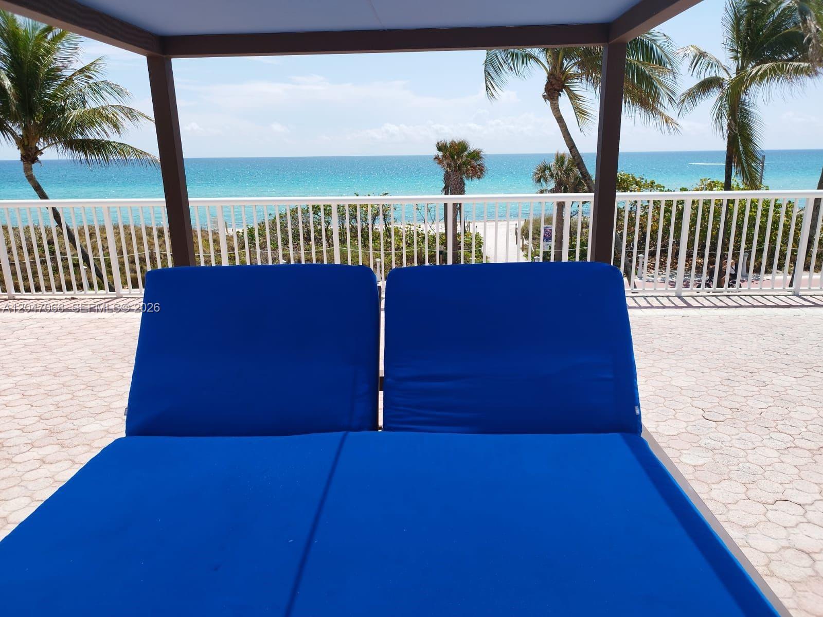 A view of the ocean from a patio featuring two blue lounge chairs — 5401 Collins Ave # 1110, Miami Beach FL 33140, MIAMI BEACH, FL