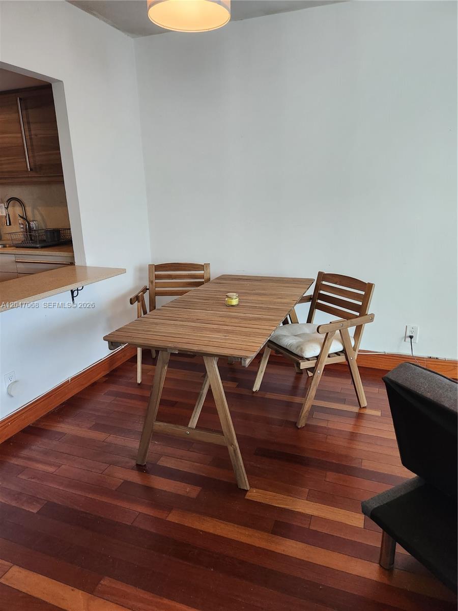 A dining area features a wooden table, two folding chairs, and dark hardwood flooring — 5401 Collins Ave # 1110, Miami Beach FL 33140, MIAMI BEACH, FL