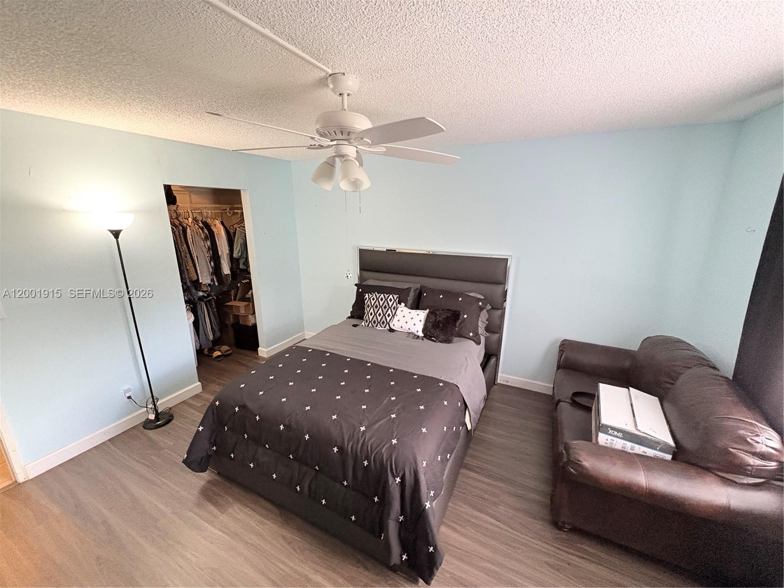 A bedroom features light blue walls, a dark bed, a brown sofa, and wood flooring — 2769 S Oakland Forest Dr # 101, Oakland Park FL 33309, OAKLAND PARK, FL