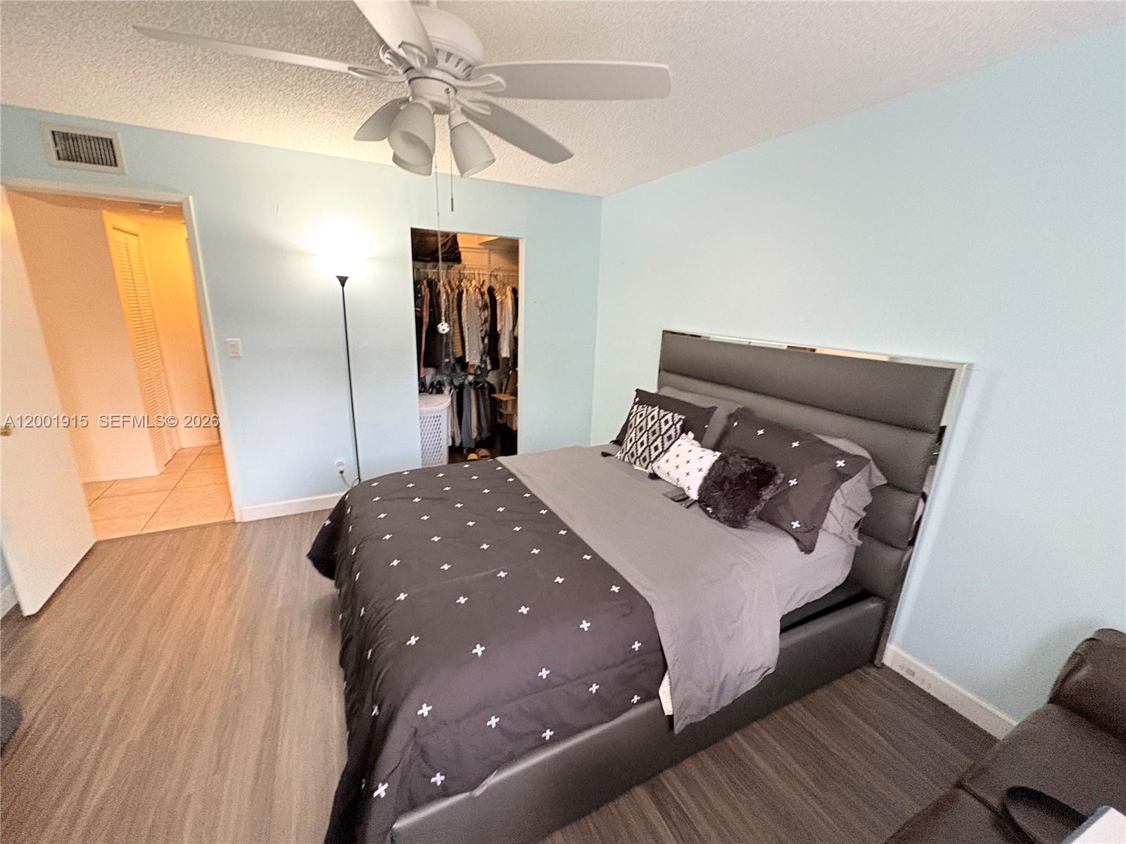 A bedroom features light blue walls, wood-look flooring, a ceiling fan, and a dark bed — 2769 S Oakland Forest Dr # 101, Oakland Park FL 33309, OAKLAND PARK, FL