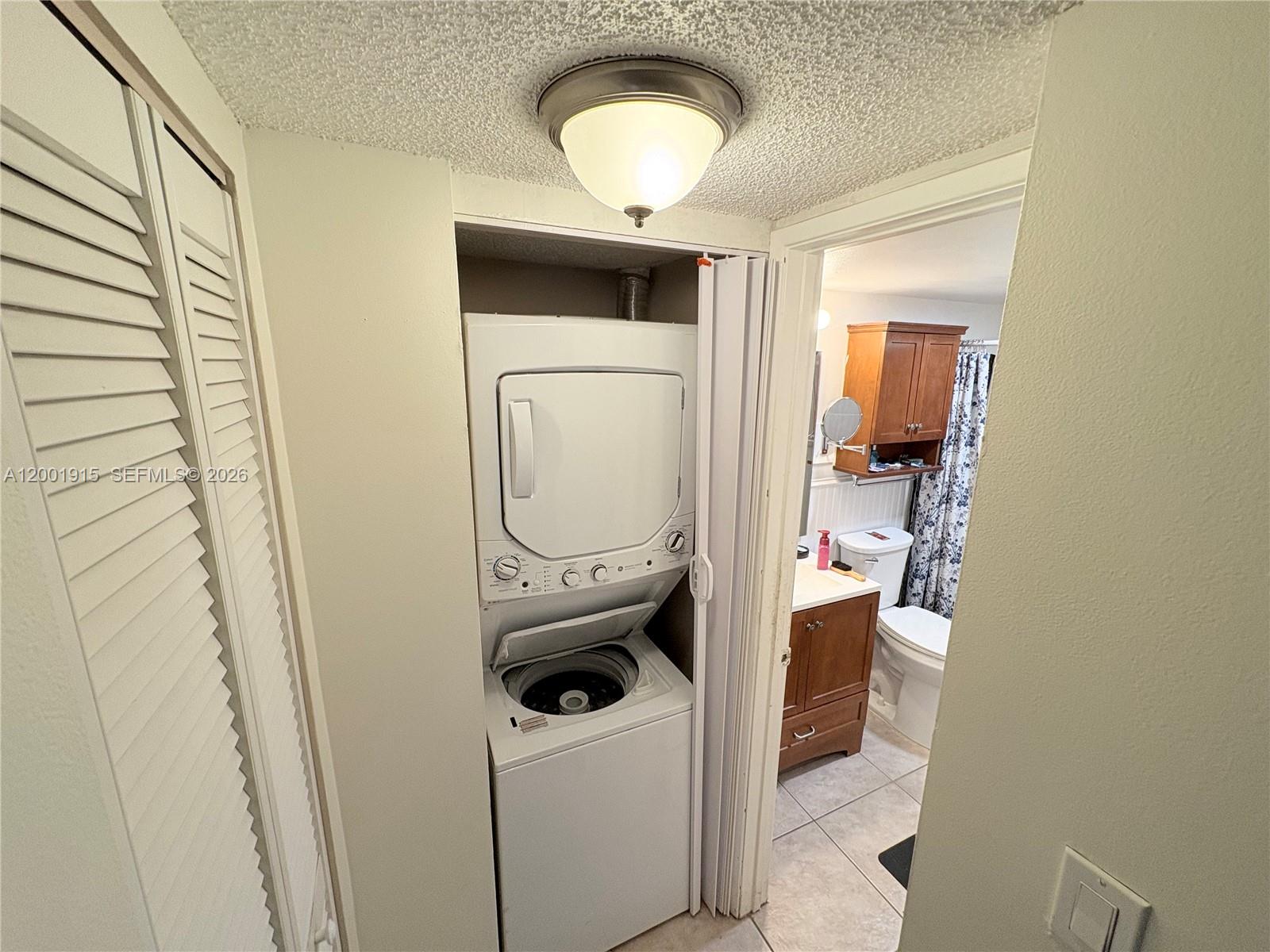 A laundry closet with a stacked washer and dryer sits beside a bathroom entrance — 2769 S Oakland Forest Dr # 101, Oakland Park FL 33309, OAKLAND PARK, FL
