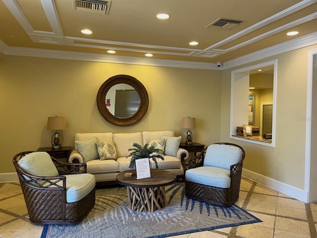 A furnished lobby area features a sofa, two armchairs, a round coffee table, and mirror — 265 MINORCA BEACH WAY UNIT 304, NEW SMYRNA BEACH, FL