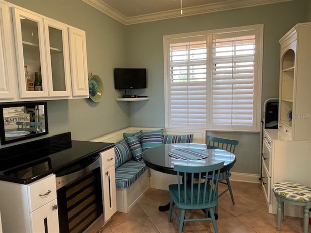 A breakfast nook features a built-in corner bench, a round table, and white cabinetry — 265 MINORCA BEACH WAY UNIT 304, NEW SMYRNA BEACH, FL