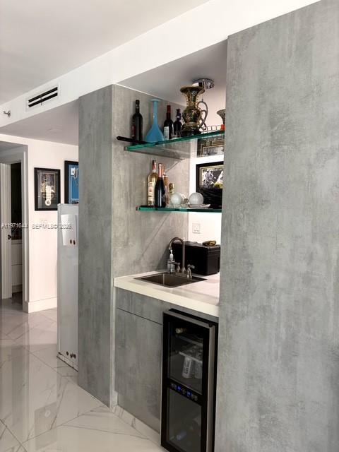 A wet bar features gray concrete-look cabinetry, glass shelving, a small sink, and a wine cooler — 19667 Turnberry Way # 27E, Aventura FL 33180, AVENTURA, FL