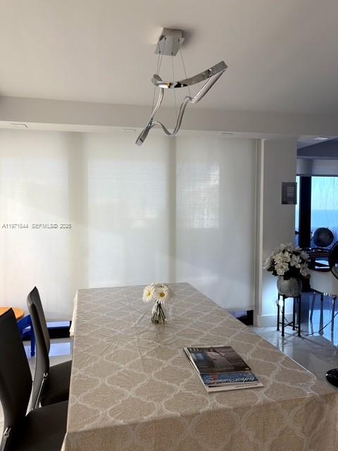 A dining room features a modern sculptural chandelier above a table with a patterned tablecloth — 19667 Turnberry Way # 27E, Aventura FL 33180, AVENTURA, FL
