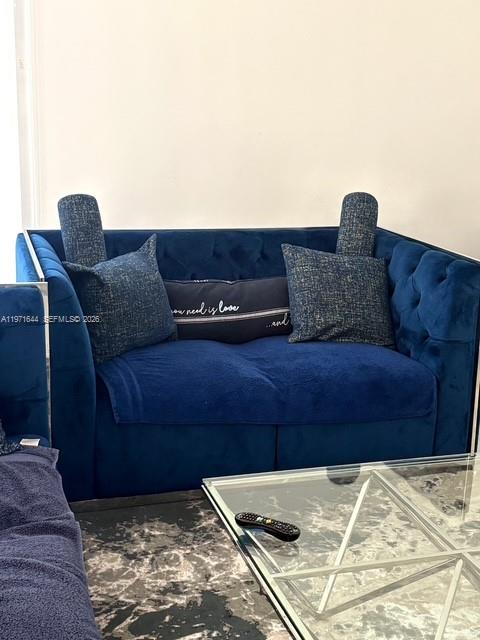 A blue tufted sofa with decorative pillows sits in a room with a glass table — 19667 Turnberry Way # 27E, Aventura FL 33180, AVENTURA, FL