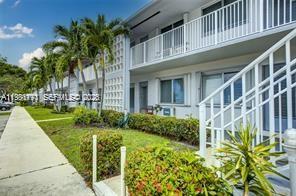 A two-story apartment building features white exterior walls, a balcony, and a sidewalk — 2020 NE 51st Ct # 203, Fort Lauderdale FL 33308, FORT LAUDERDALE, FL