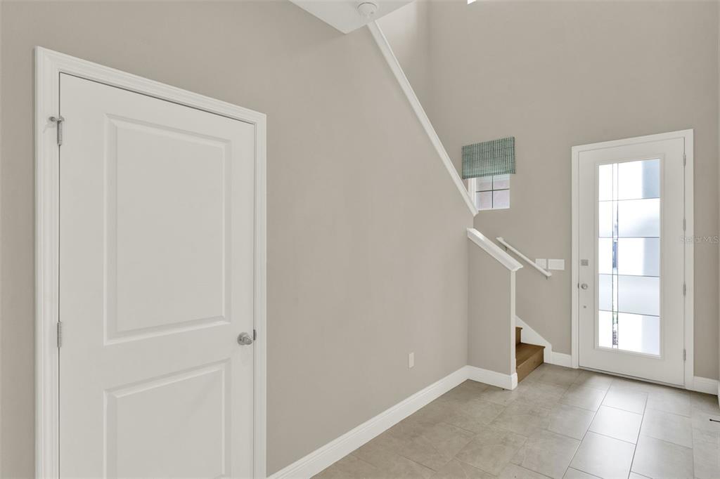 An entryway features a white door, a staircase, and a glass-paneled front door — 2063 KEYSTONE PASS BOULEVARD, MINNEOLA, FL