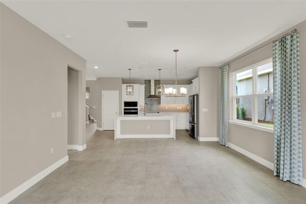 A modern kitchen with a white island, stainless steel appliances, and gray tile flooring — 2063 KEYSTONE PASS BOULEVARD, MINNEOLA, FL