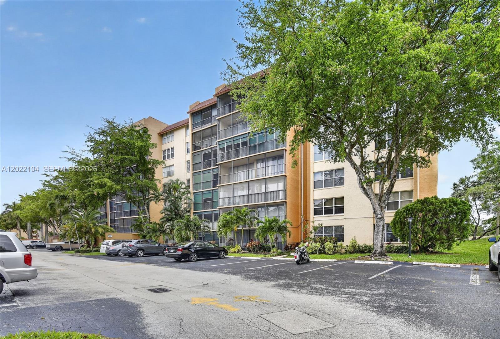 An exterior view of a multi-story apartment building with a parking lot in front — 3771 Environ Blvd # 355, Lauderhill FL 33319, LAUDERHILL, FL