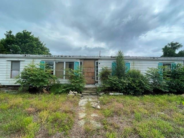 A single-story manufactured home sits on a grassy lot with trees and a chain-link fence — 12024 LAKEVIEW DRIVE, LEESBURG, FL