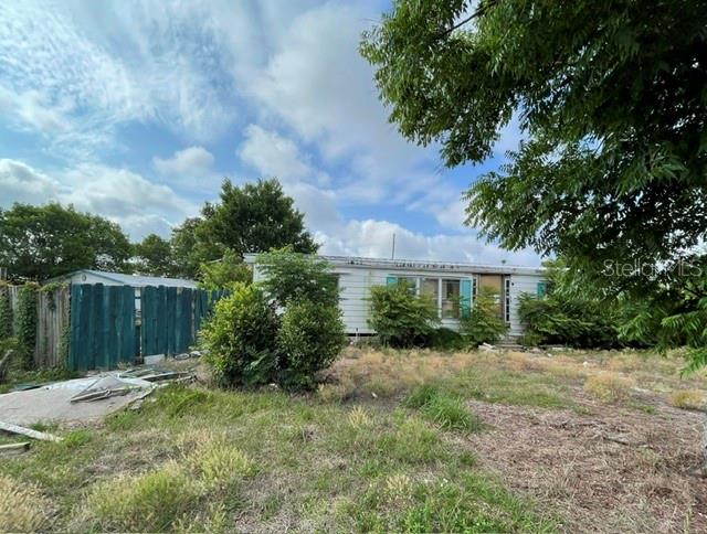 A single-story house with a blue fence stands on a grassy lot under a cloudy sky — 12024 LAKEVIEW DRIVE, LEESBURG, FL