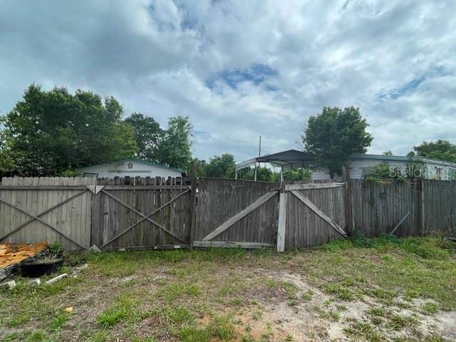 A wooden fence stands in front of a mobile home under a cloudy sky — 12024 LAKEVIEW DRIVE, LEESBURG, FL
