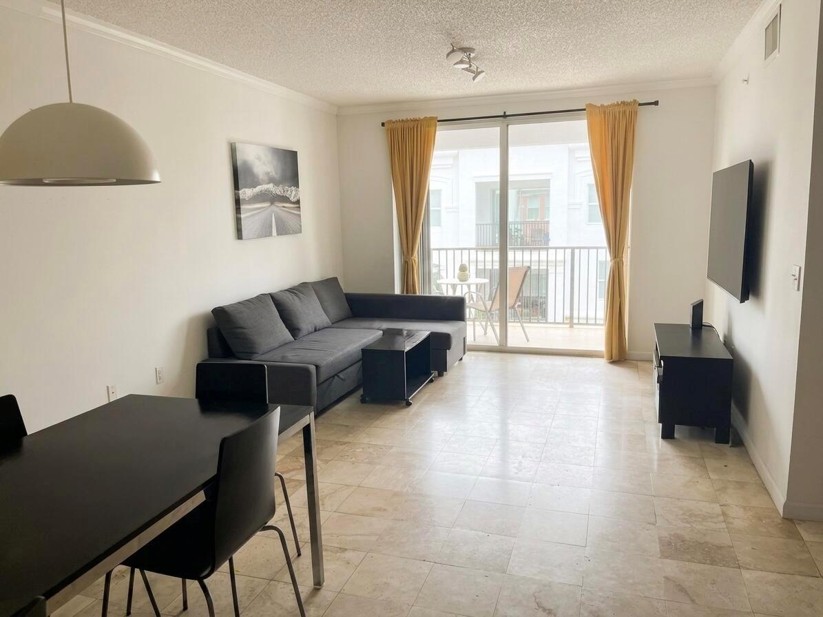 A living room with tile floors, a gray sectional sofa, and a sliding glass balcony door — 17100 N Bay Road # 1911, Sunny Isles Beach FL 33160, SUNNY ISLES BEACH, FL