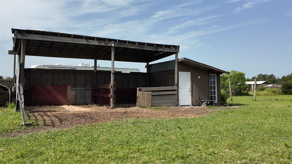 A wooden barn with an open-sided stall area and an attached enclosed storage room — 345 TROTTING TRAIL, OSTEEN, FL