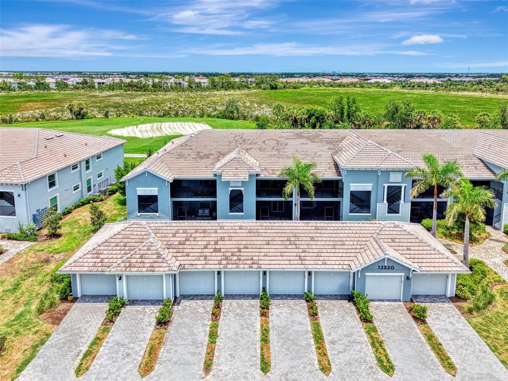 An aerial view shows a multi-unit residential building with a row of garages and balconies — 12520 GALAPAGOS COURT UNIT 102, VENICE, FL