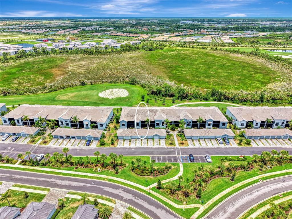 An aerial view shows a row of townhomes with a circled unit facing a golf course — 12520 GALAPAGOS COURT UNIT 102, VENICE, FL
