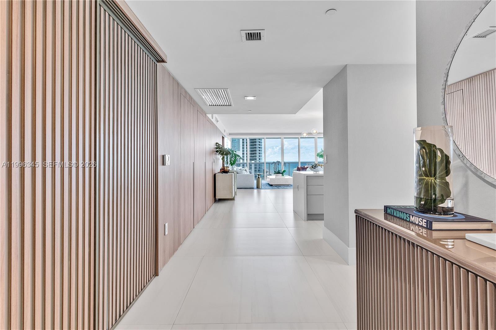 A hallway with wood-slatted walls leads to an open living area with ocean views — 1830 S Ocean Dr # 1501, Hallandale Beach FL 33009, HALLANDALE BEACH, FL