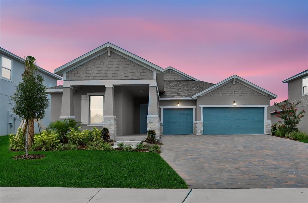 A single-story house with a gray exterior, blue garage doors, and a paved driveway — 7418 SEA MANATEE STREET, PARRISH, FL