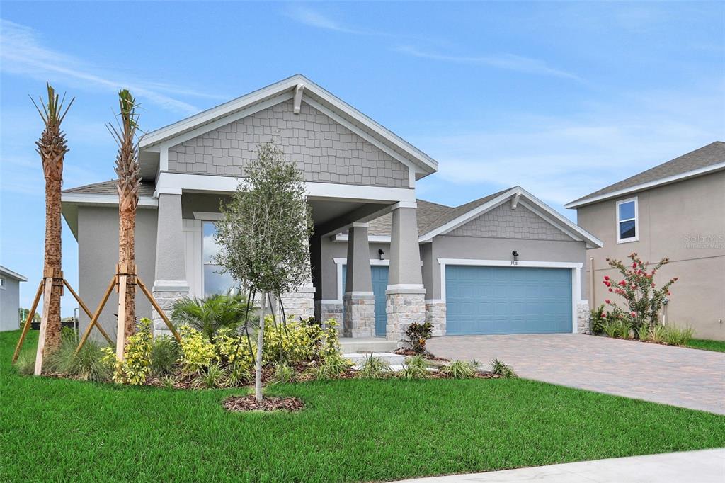 A single-story house with a blue garage door, stone accents, and a covered front porch — 7418 SEA MANATEE STREET, PARRISH, FL