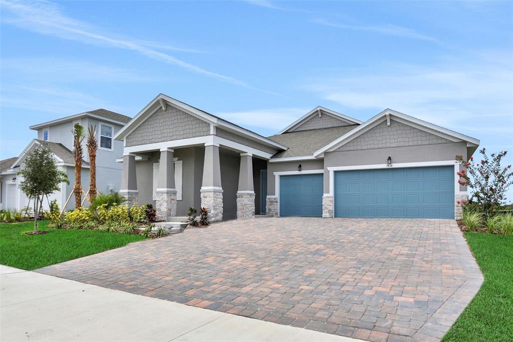 A single-story house with a gray exterior, stone-based columns, and a paved driveway — 7418 SEA MANATEE STREET, PARRISH, FL