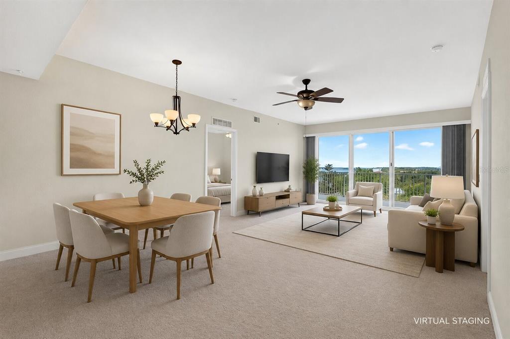 A virtually staged living and dining room with carpeted floors and a balcony view — 2801 S RIDGEWOOD AVENUE UNIT 504, SOUTH DAYTONA, FL