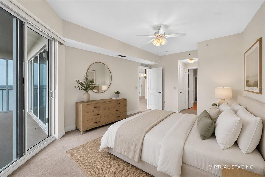 A virtually staged bedroom features a bed, dresser, ceiling fan, and sliding glass balcony doors — 2801 S RIDGEWOOD AVENUE UNIT 504, SOUTH DAYTONA, FL