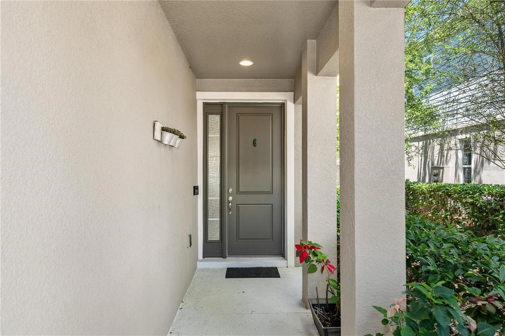 A covered entryway features a gray front door with a side light and a porch — 572 LAKE WILDMERE COVE, LONGWOOD, FL