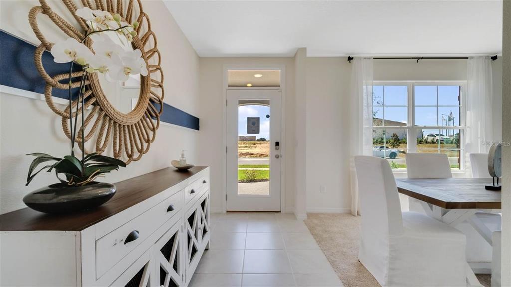 A bright entryway features a white console table, a rope mirror, and a dining area — 572 LAKE WILDMERE COVE, LONGWOOD, FL