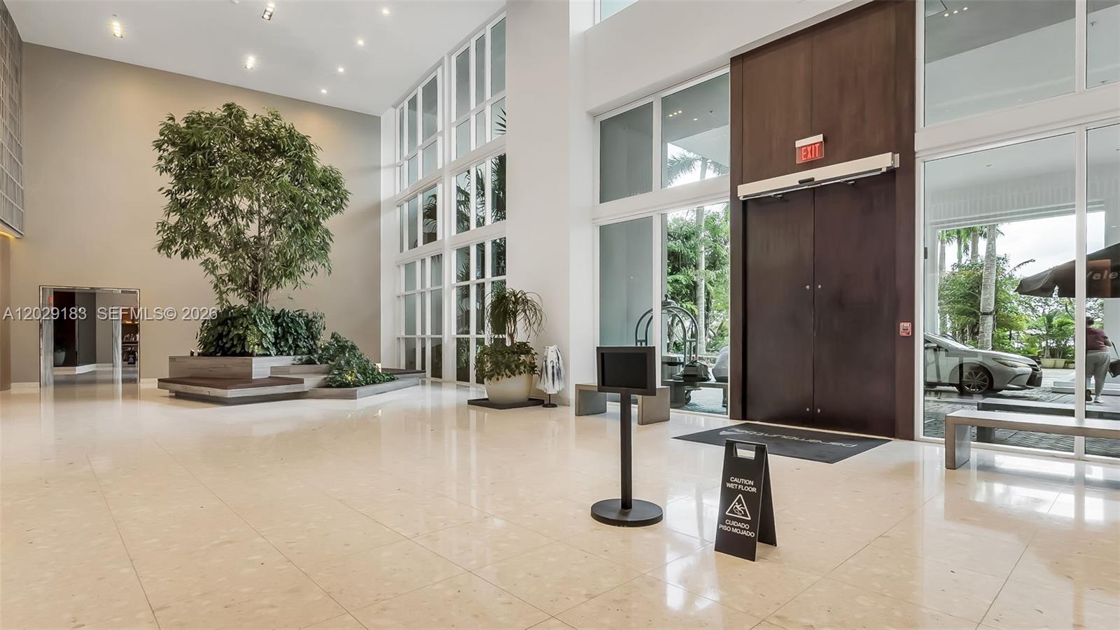 A modern building lobby features a large indoor tree, polished tile floors, and glass walls — 2020 N Bayshore Dr # 2603, Miami FL 33137, MIAMI, FL