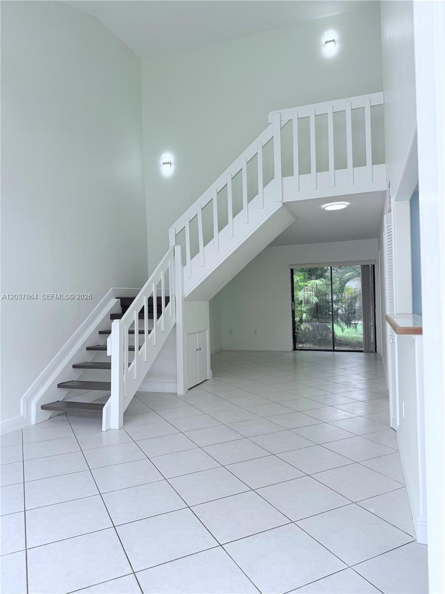 A room with white tile floors features a staircase leading to an upper landing — 10532 SW 112th Ave, Miami FL 33176, MIAMI, FL