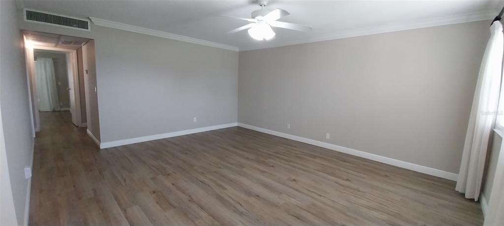 An empty room features light-colored walls, wood-look flooring, and a ceiling fan — 1811 BEDFORD LANE UNIT 157, SUN CITY CENTER, FL