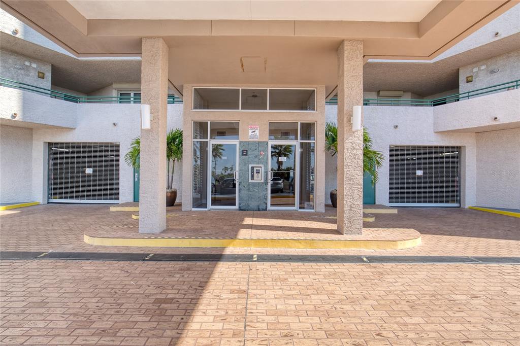 A covered entrance with two glass doors, stone pillars, and closed metal security shutters — 3315 S ATLANTIC AVENUE UNIT 705, DAYTONA BEACH, FL