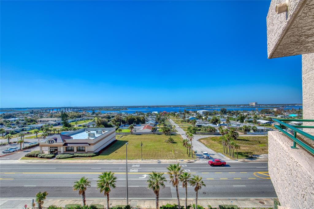 An elevated view overlooking a road, a commercial building, a vacant lot, and the ocean — 3315 S ATLANTIC AVENUE UNIT 705, DAYTONA BEACH, FL