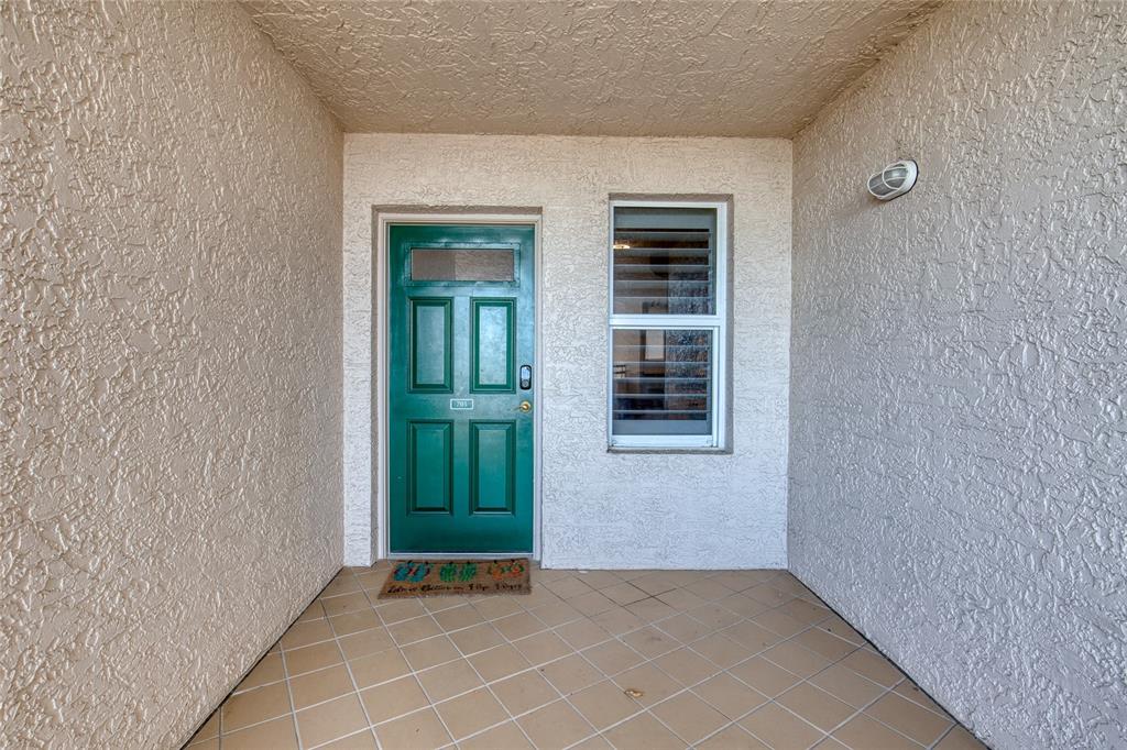 A green front door with a window and a nearby window on a tiled porch — 3315 S ATLANTIC AVENUE UNIT 705, DAYTONA BEACH, FL