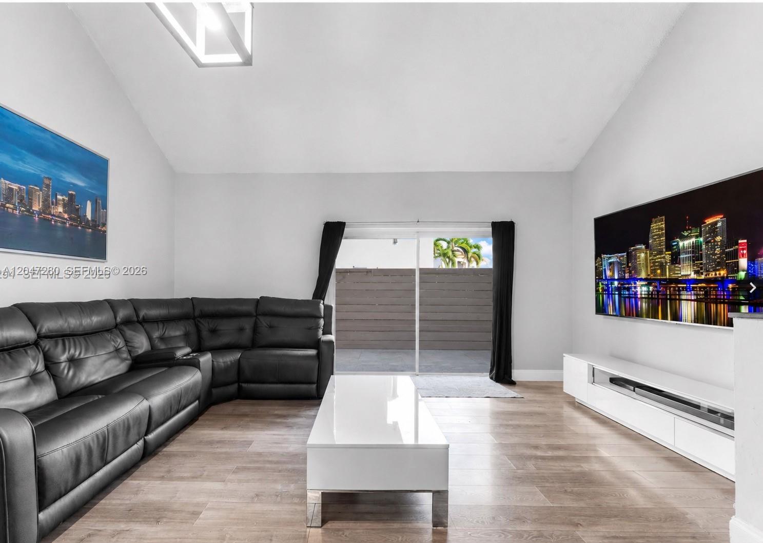 A living room features a black sectional sofa, white coffee table, and a large television — 12909 SW 64th Ln, Miami FL 33183, MIAMI, FL
