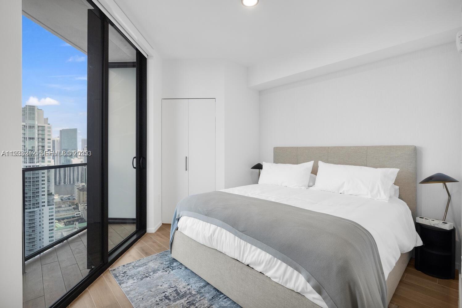 A modern bedroom features a bed, a closet, and a balcony with city skyline views — 398 NE 5th St # 1417, Miami FL 33132, MIAMI, FL