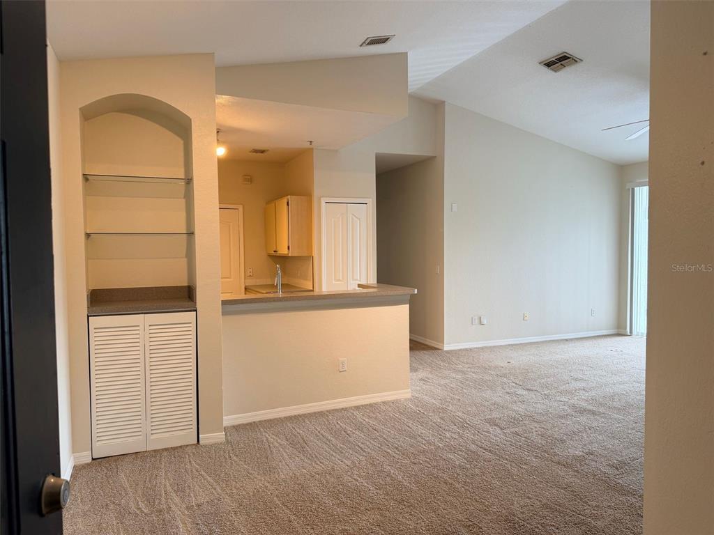 An interior view shows a carpeted living area with an arched built-in and kitchen pass-through — 2651 MAITLAND CROSSING WAY UNIT 303, ORLANDO, FL
