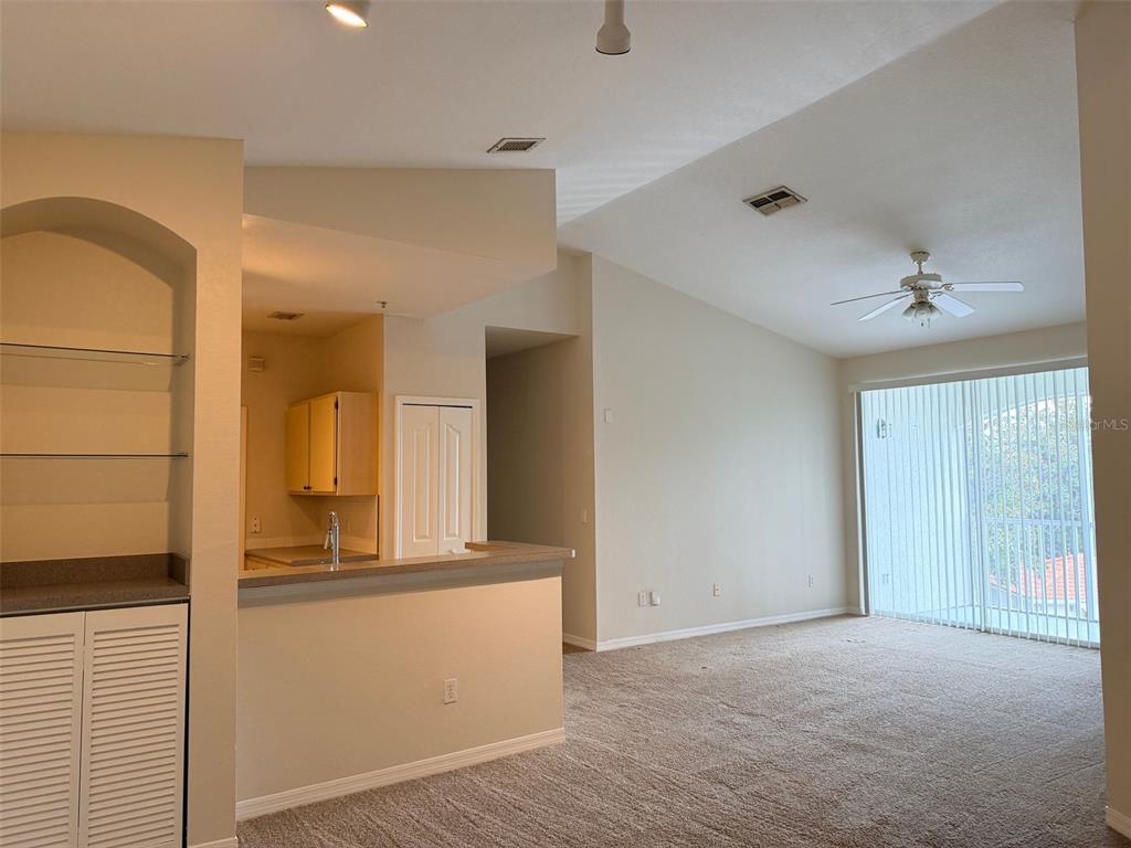 An interior view shows a carpeted living area with a kitchen pass-through and sliding glass doors — 2651 MAITLAND CROSSING WAY UNIT 303, ORLANDO, FL