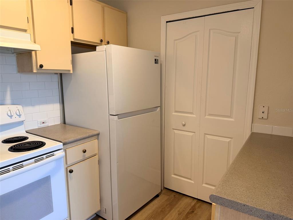 A kitchen features white appliances, light-colored cabinets, a gray countertop, and a white closet door — 2651 MAITLAND CROSSING WAY UNIT 303, ORLANDO, FL