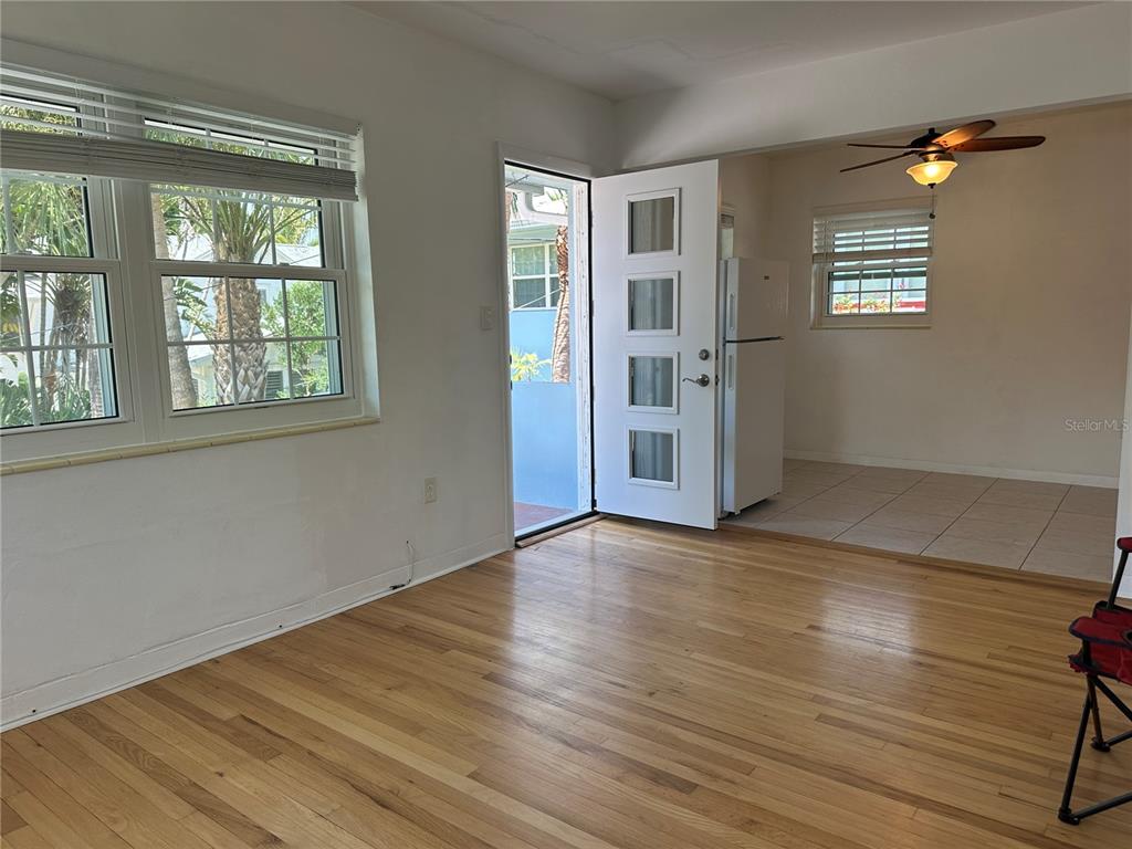 A living room with hardwood floors leads to a tiled kitchen through an open doorway — 1800 PASS A GRILLE WAY UNIT 5, ST PETE BEACH, FL
