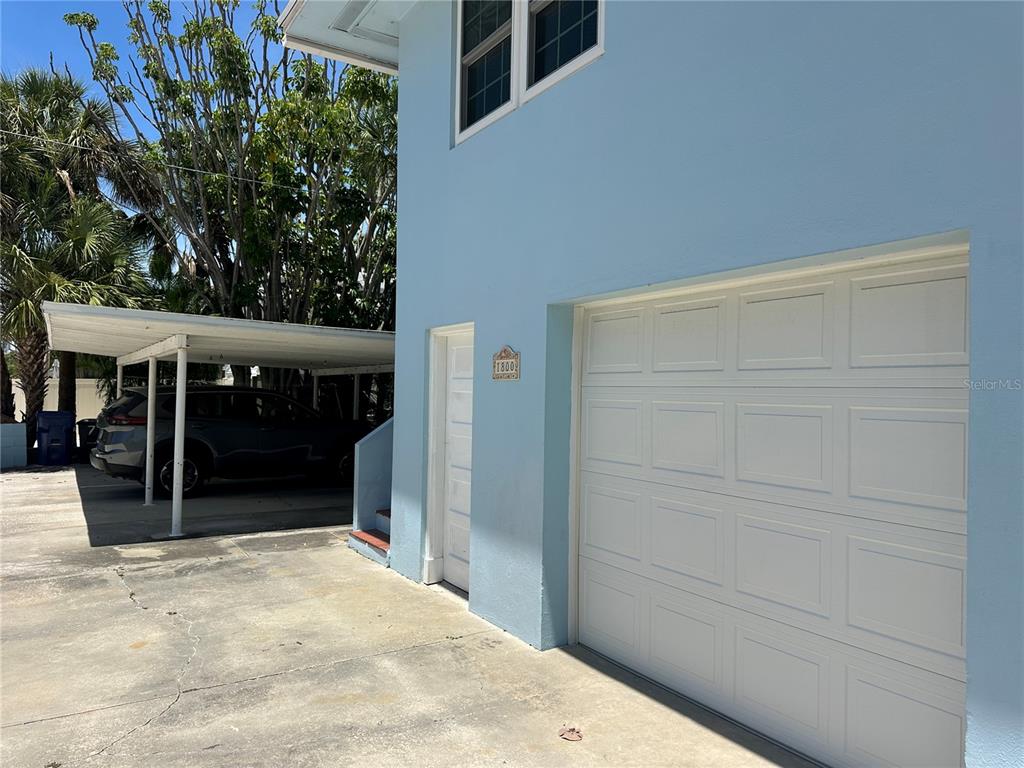 A light blue two-story building features a garage, a side door, and a carport — 1800 PASS A GRILLE WAY UNIT 5, ST PETE BEACH, FL
