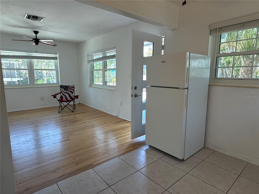 A room features hardwood floors, a white refrigerator, and a chair with an American flag — 1800 PASS A GRILLE WAY UNIT 5, ST PETE BEACH, FL
