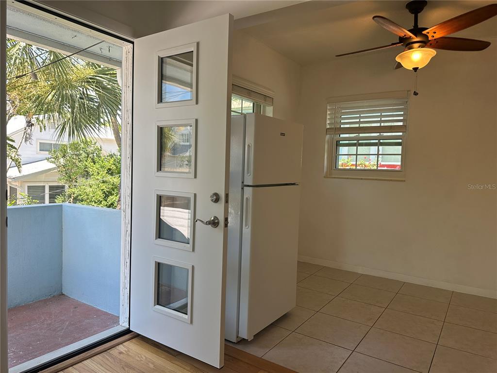 A white refrigerator stands in a tiled room next to an open door with windows — 1800 PASS A GRILLE WAY UNIT 5, ST PETE BEACH, FL