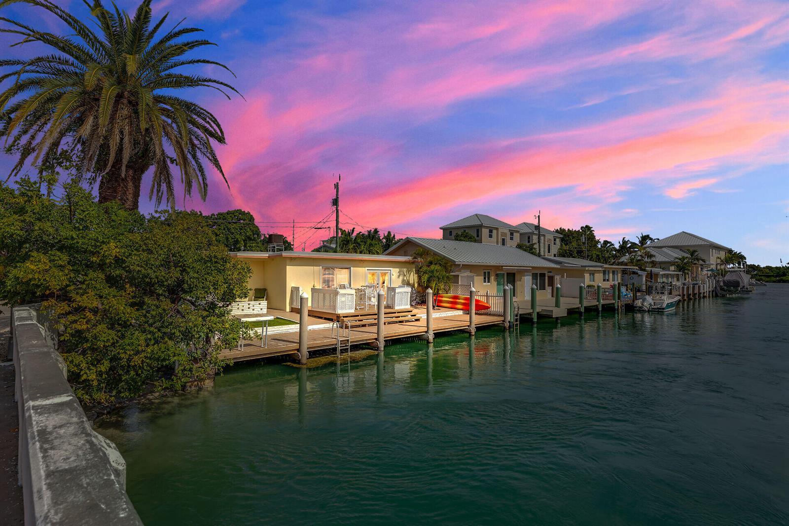 A waterfront house with a wooden deck and a palm tree under a sunset sky — 11725 3rd Avenue Ocean, Marathon FL 33050, MARATHON, FL